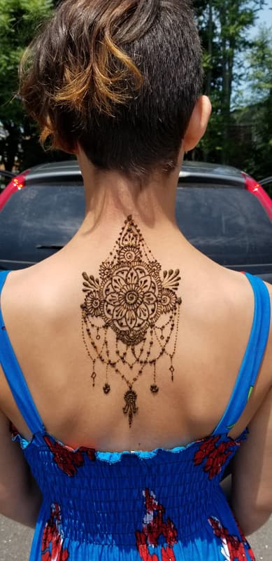 Mandala henna design with draping chains across a woman's upper back and neck